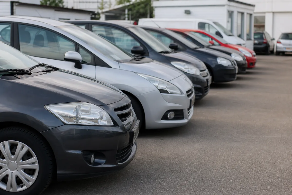 Alignement de voitures d’occasion compactes sur un parking de vente en France